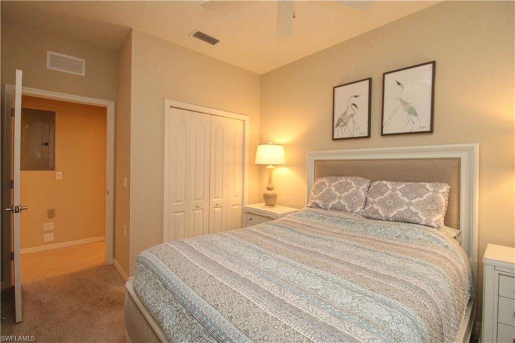 Carpeted bedroom featuring a closet, ceiling fan, visible vents, and electric panel