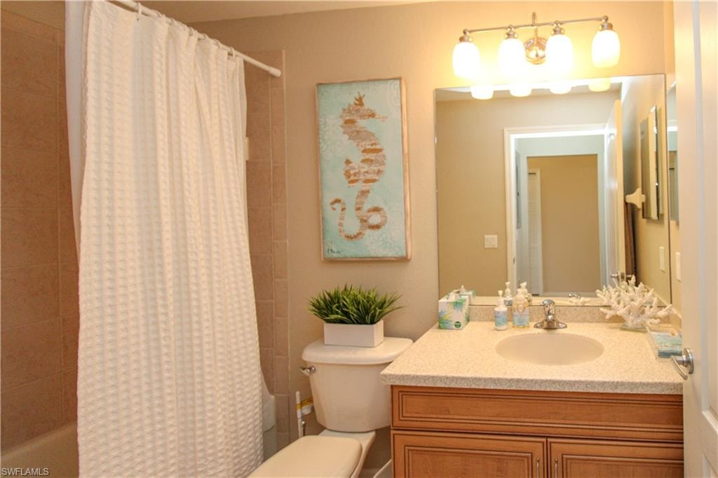 Full bath with shower / bath combo with shower curtain, vanity, and toilet