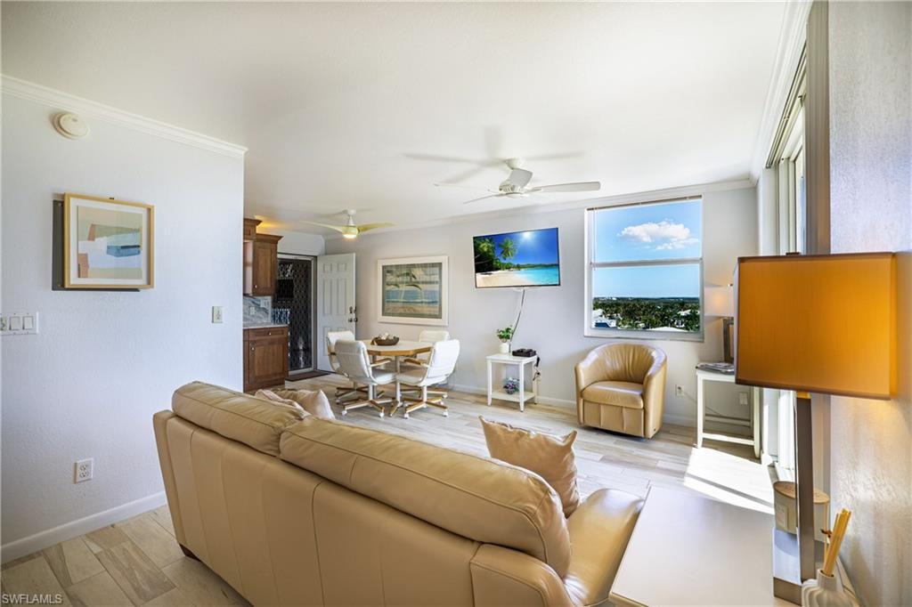 Living room with ornamental molding, light wood-type flooring, and ceiling fan