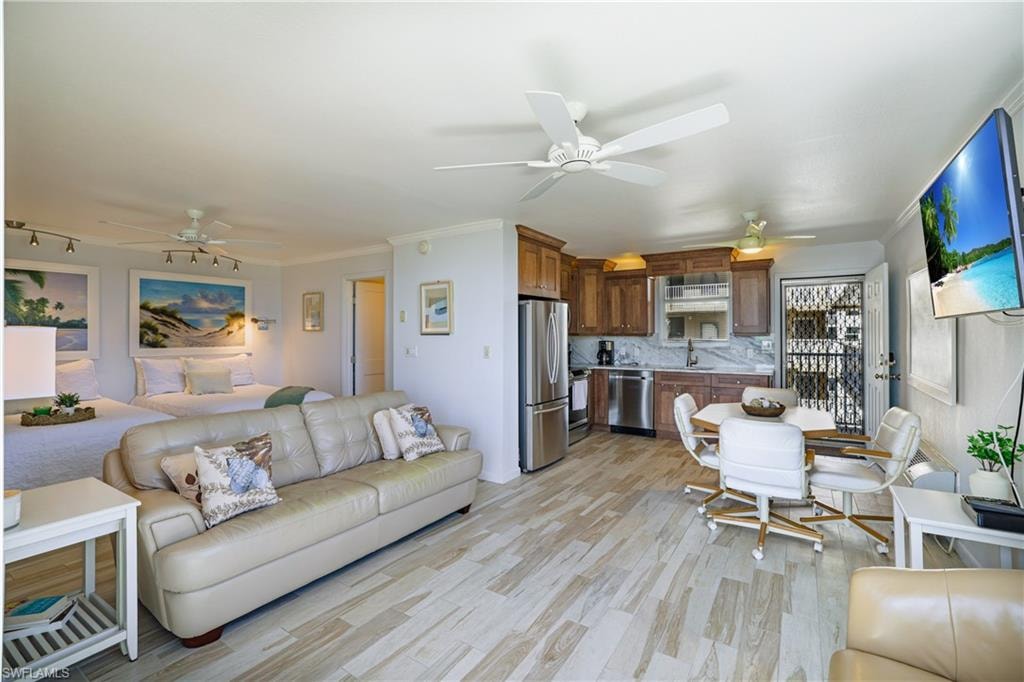 Living room with crown molding, a ceiling fan, and light wood finished floors