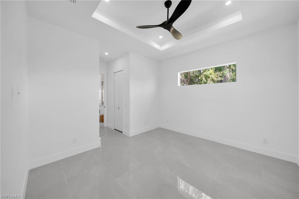 Unfurnished room with ceiling fan, recessed lighting, and a tray ceiling