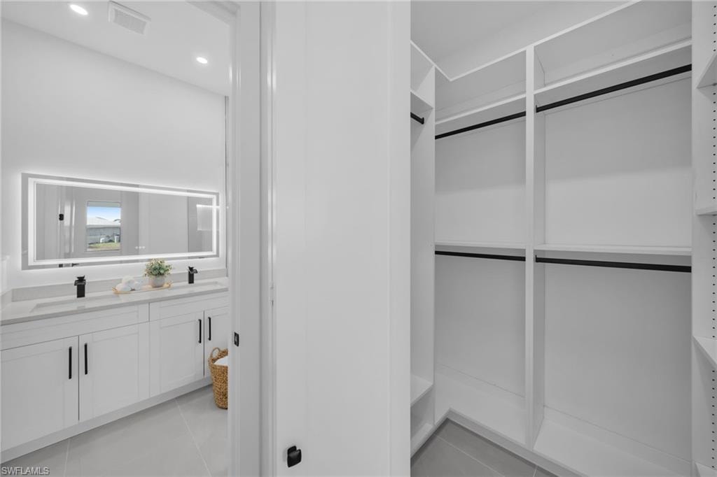 Walk in closet with light tile patterned floors and a sink