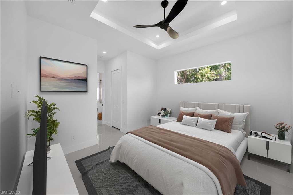 Bedroom featuring a tray ceiling, ensuite bath, ceiling fan, recessed lighting, and a closet