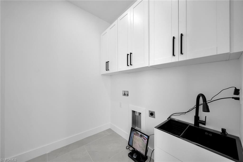 Laundry room featuring hookup for an electric dryer, washer hookup, light tile patterned floors, and cabinet space