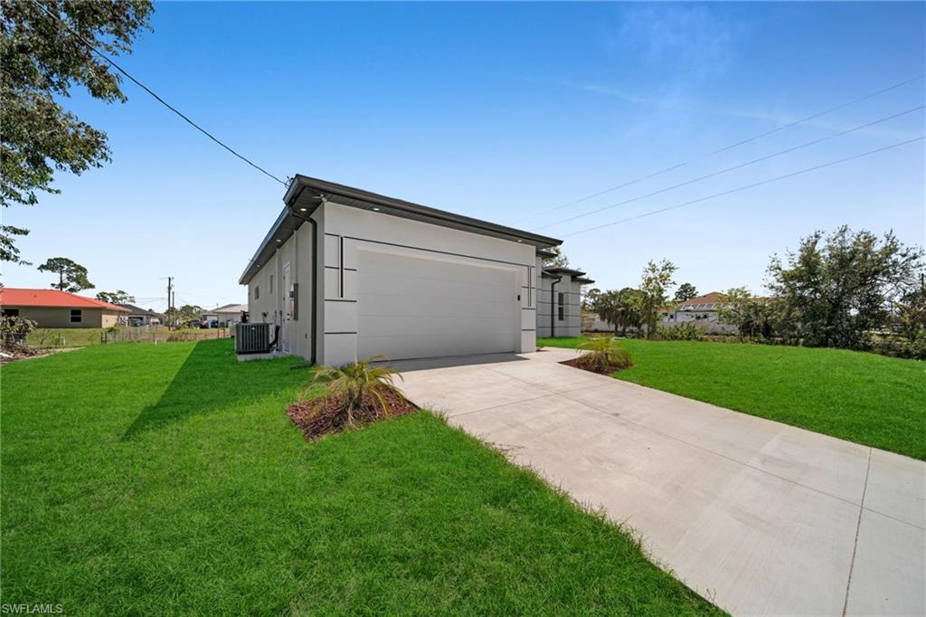 View of side of home with a lawn, a garage, driveway, and stucco siding