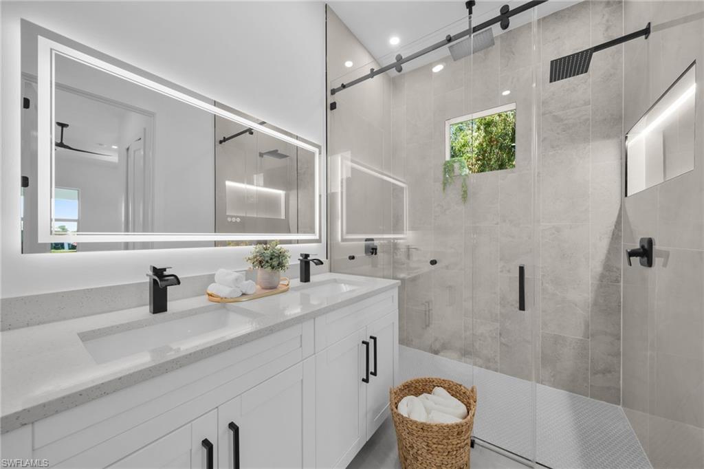 Full bathroom featuring double vanity and a stall shower