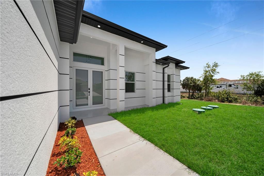 Property entrance featuring a lawn and stucco siding