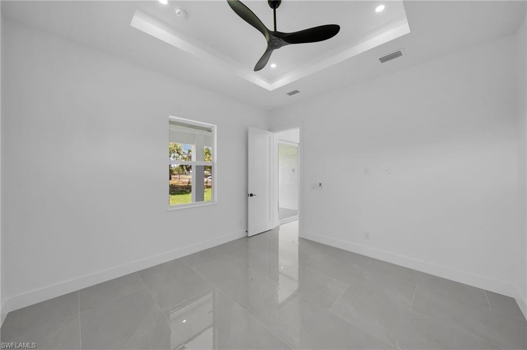 Spare room with recessed lighting, ceiling fan, and a tray ceiling