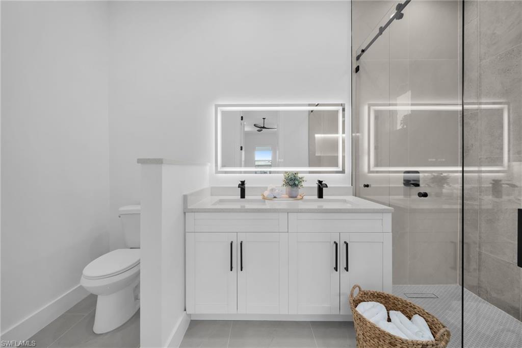 Full bathroom featuring double vanity, a stall shower, and light tile patterned flooring