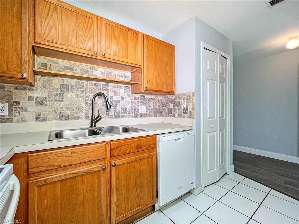Kitchen with white appliances, light countertops, light tile patterned floors, and wood finish cabinets