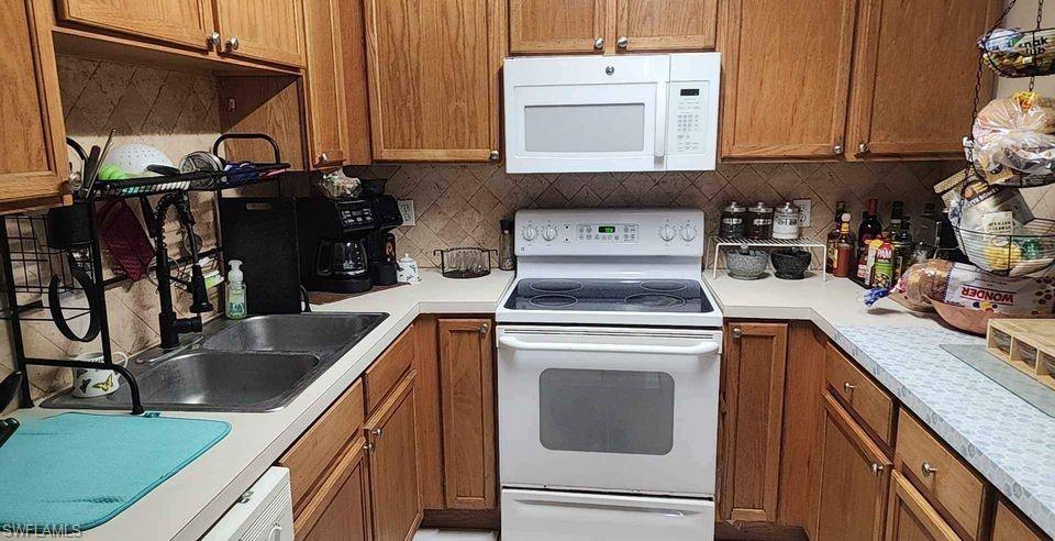 Kitchen featuring wood finish cabinets, appliances, light countertops, and decorative backsplash