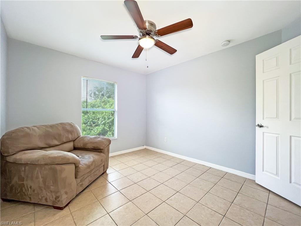 Den with ceiling fan and light tile patterned flooring
