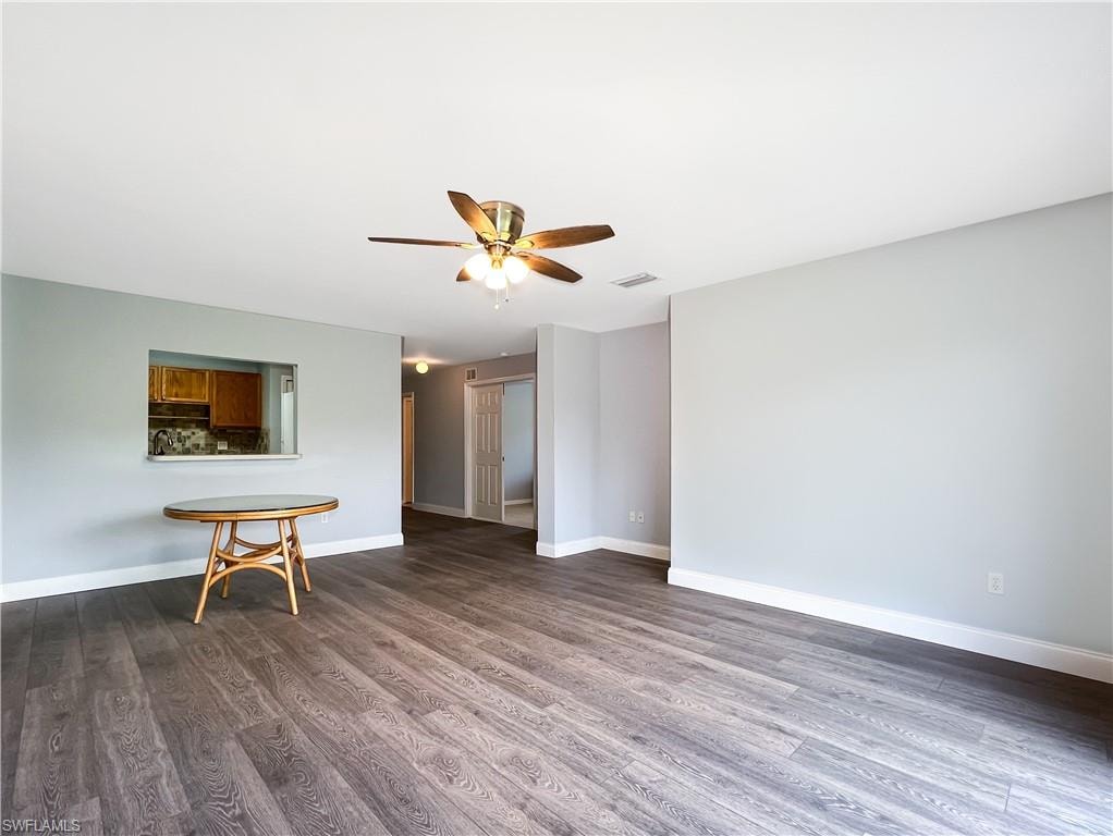 Unfurnished living room featuring dark wood-type flooring and ceiling fan
