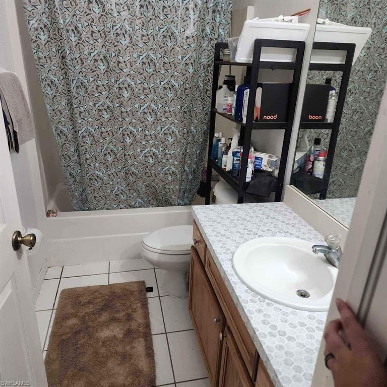 Bathroom featuring vanity, light tile patterned floors, and shower / bath combo with shower curtain