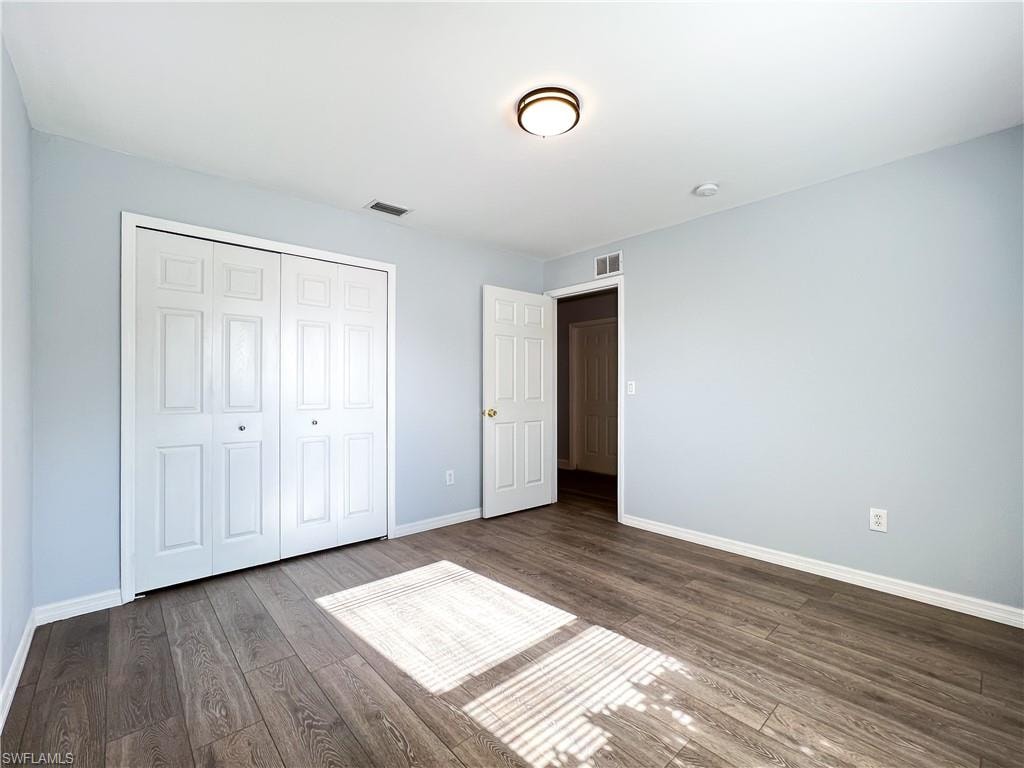 Unfurnished bedroom featuring dark wood-style flooring and a closet