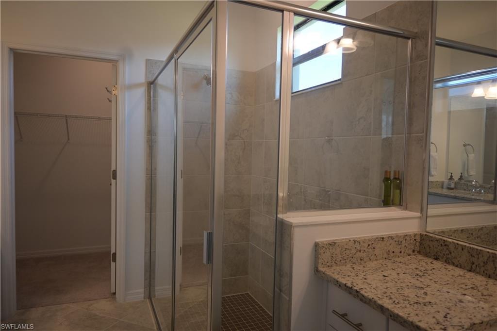 Master Bathroom with vanity, a walk in closet, and a shower stall