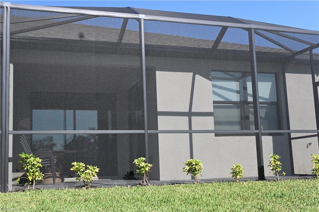 View of side of home with a sunroom, glass enclosure, and stucco siding