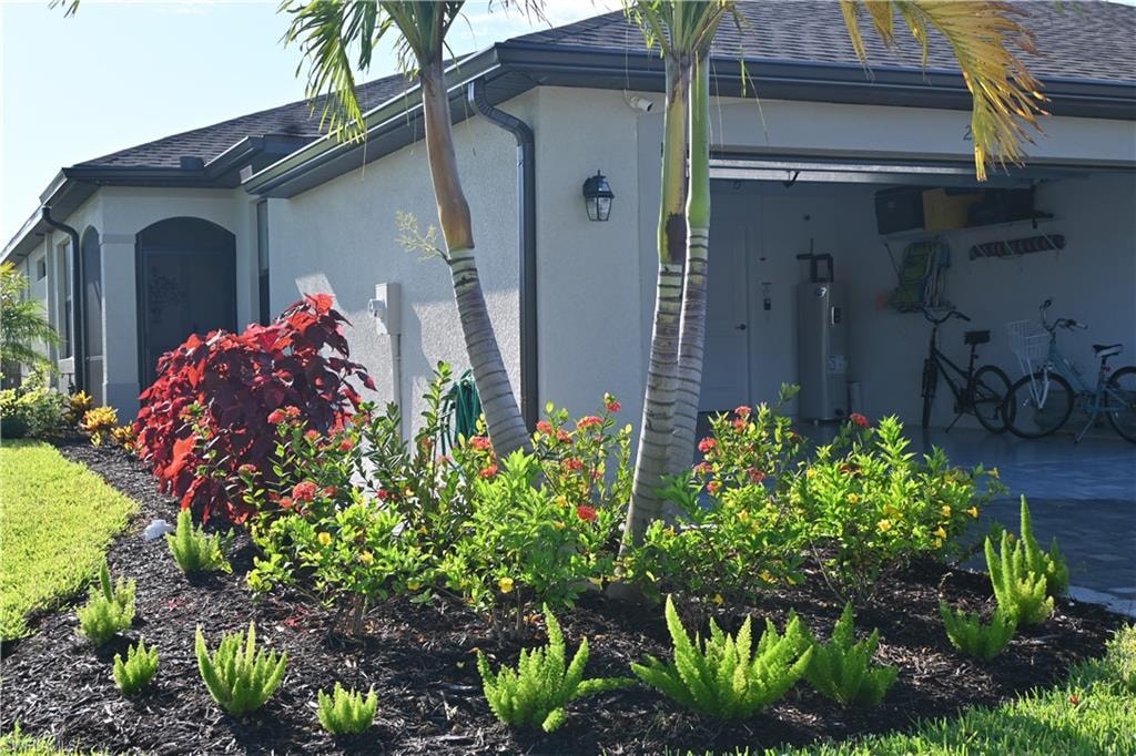 View of home's exterior with stucco siding, a shingled roof, water heater, and an attached garage