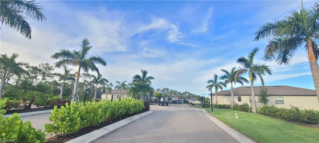 View of asphalt street with a gate, a gated entry, curbs, and a residential view