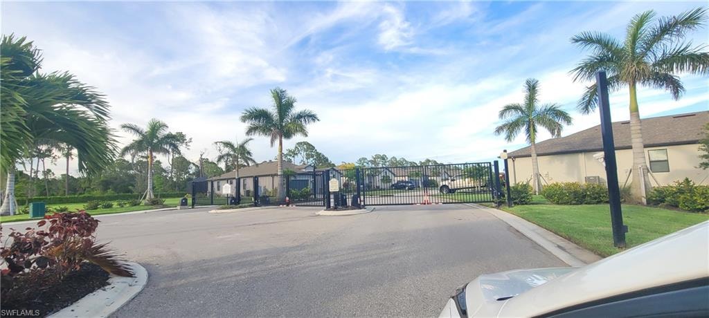 View of asphalt road with a gate, a gated entry, and curbs
