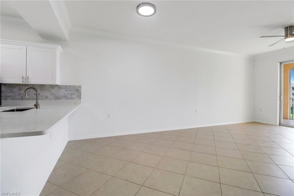 Unfurnished dining area with sink, ceiling fan, ornamental molding, and light tile patterned floors