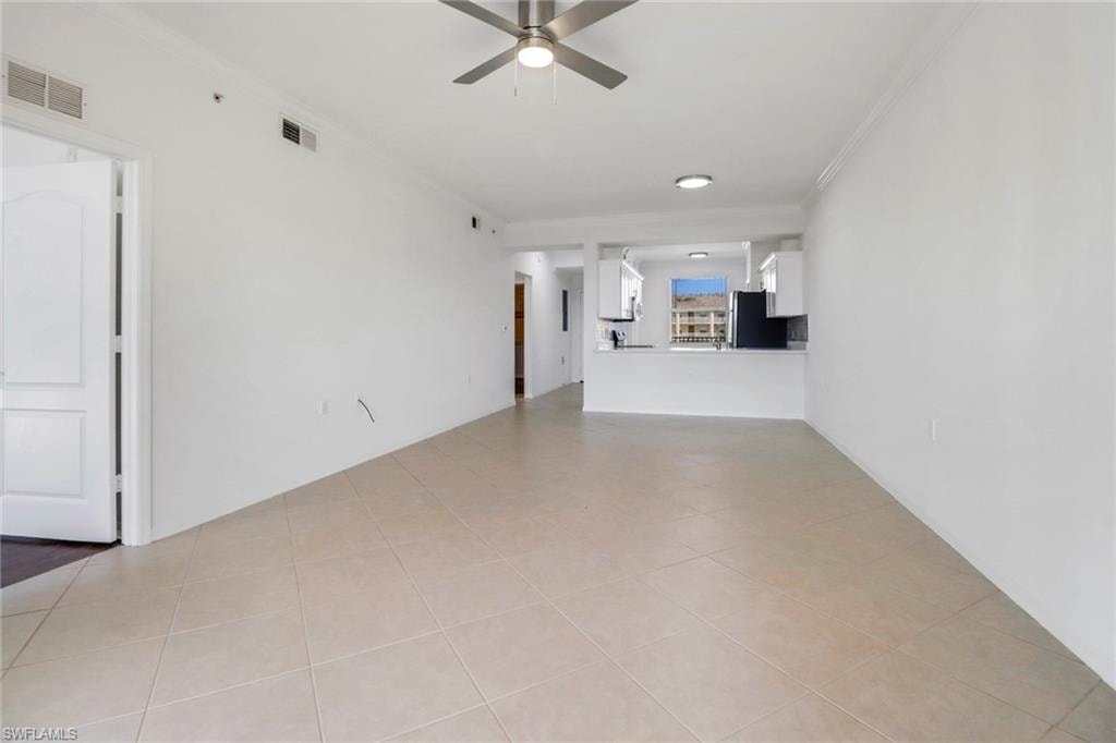 Unfurnished living room with crown molding, light tile patterned floors, and ceiling fan