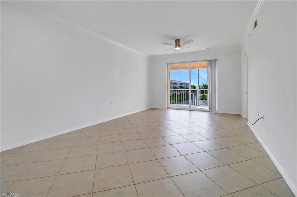 Tiled empty room with ceiling fan and ornamental molding