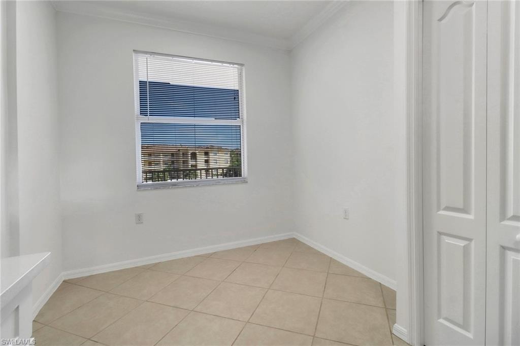 Tiled empty room with ornamental molding and a wealth of natural light