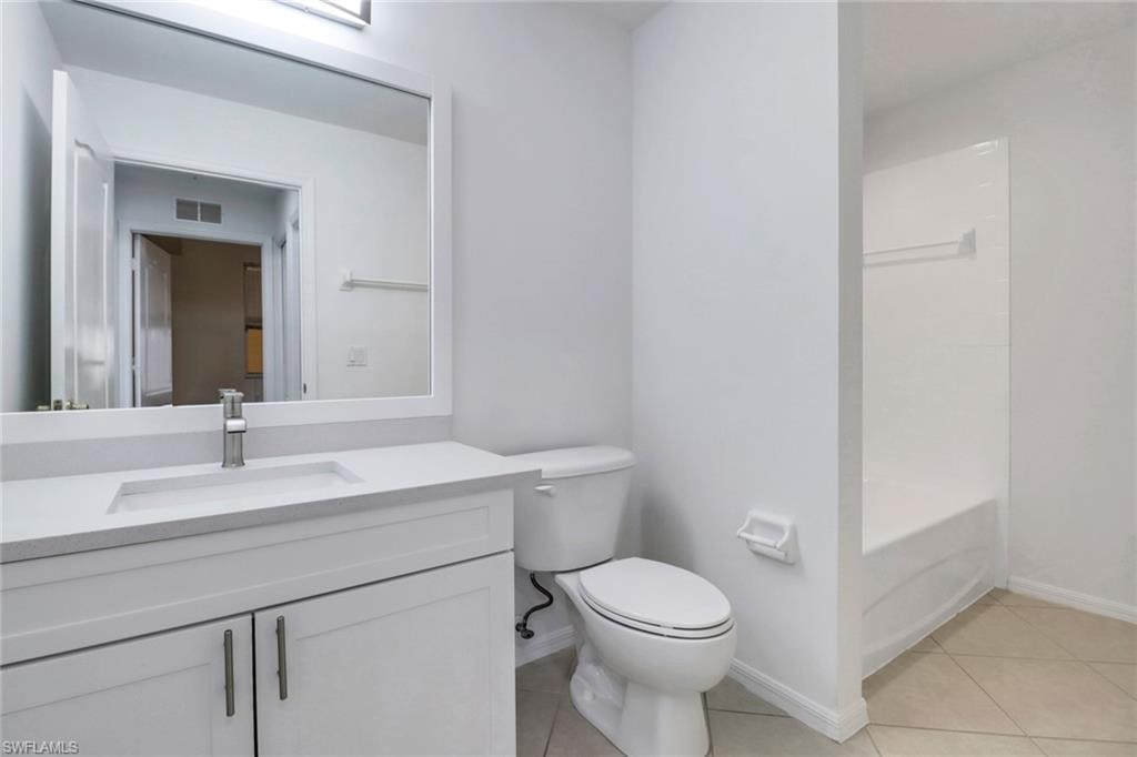 Full bathroom with tile patterned floors, vanity, shower / washtub combination, and toilet