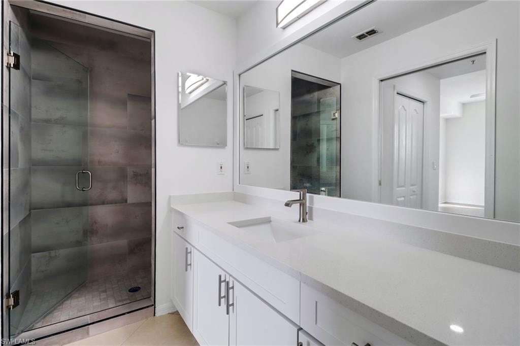 Bathroom featuring tile patterned floors, a shower with door, and vanity