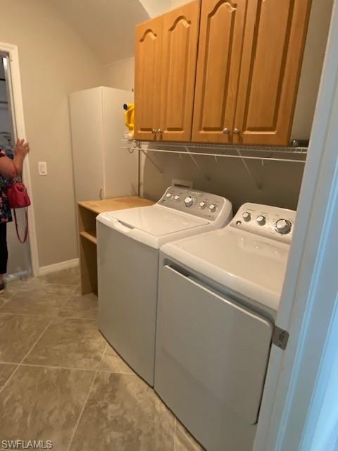Laundry area with cabinets, light tile flooring, and washer and clothes dryer