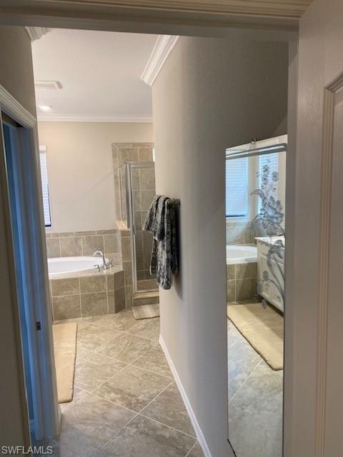 Bathroom with tile flooring, plenty of natural light, independent shower and bath, and crown molding