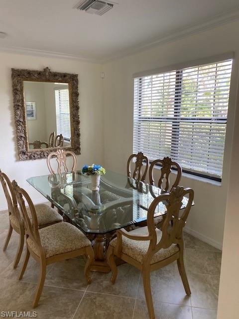 Dining space with tile flooring, a healthy amount of sunlight, and crown molding