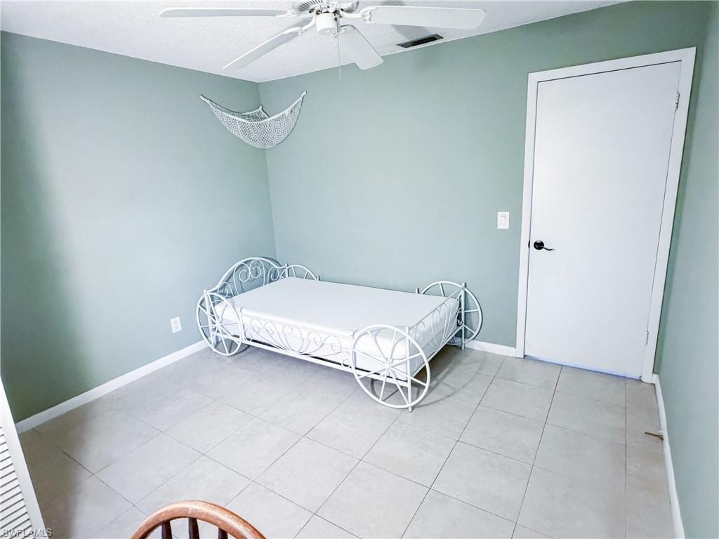 Guest bedroom #2 featuring a ceiling fan, a textured ceiling, and light tile patterned floors