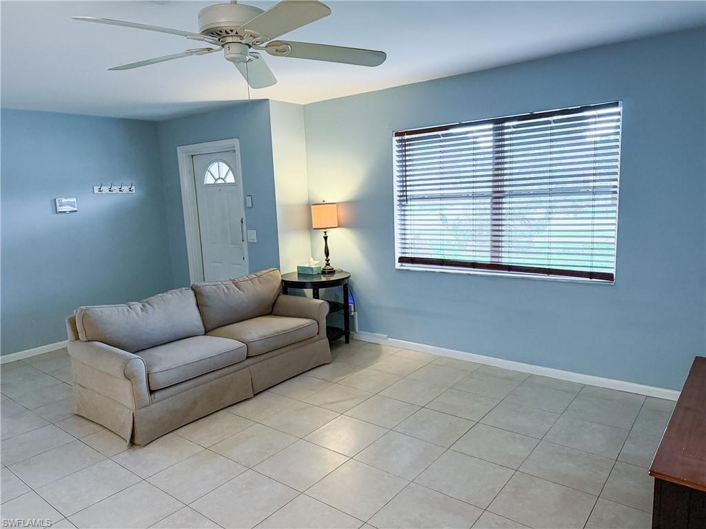 Open living room with ceiling fan and light tile patterned floors