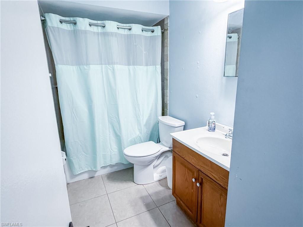 Full bathroom with vanity, light tile patterned flooring, and a shower