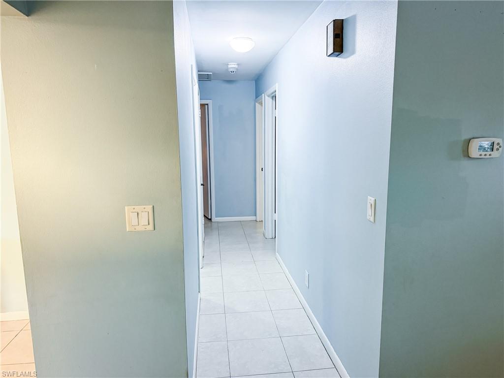 Hallway with light tile patterned flooring and baseboards