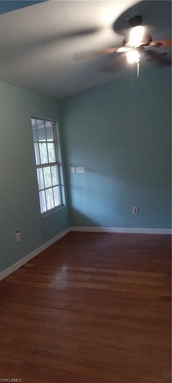Unfurnished room with dark wood-style flooring and a ceiling fan
