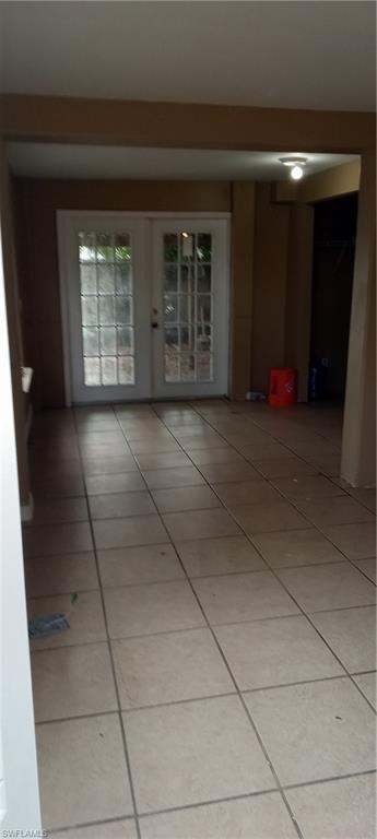 Empty room with light tile patterned floors and french doors