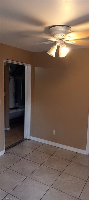 Empty room with ceiling fan and light tile patterned floors
