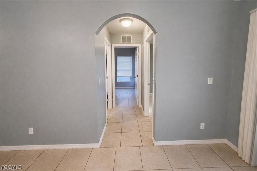 Hallway with arched walkways and light tile patterned floors
