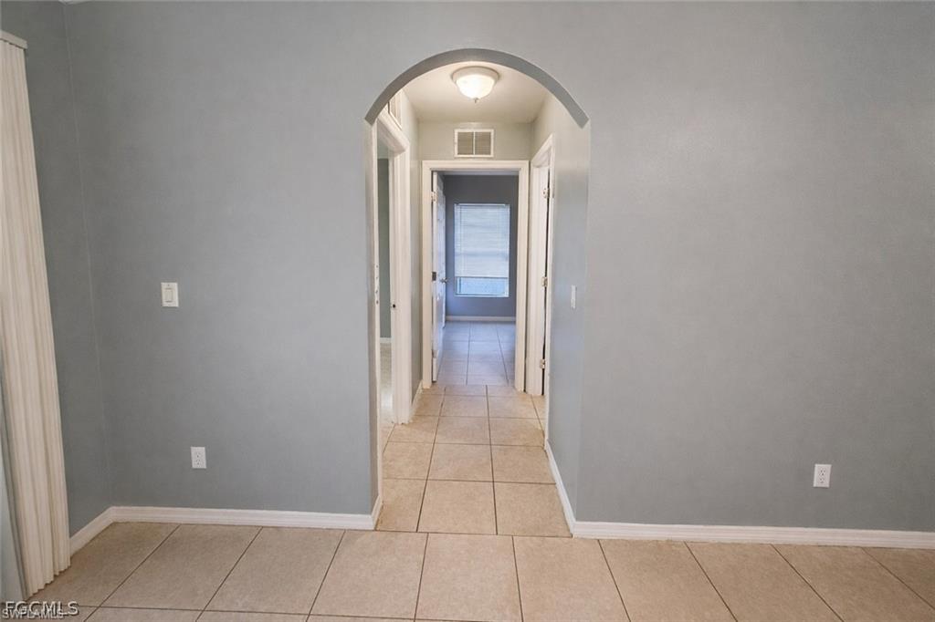 Hallway featuring arched walkways and light tile patterned floors