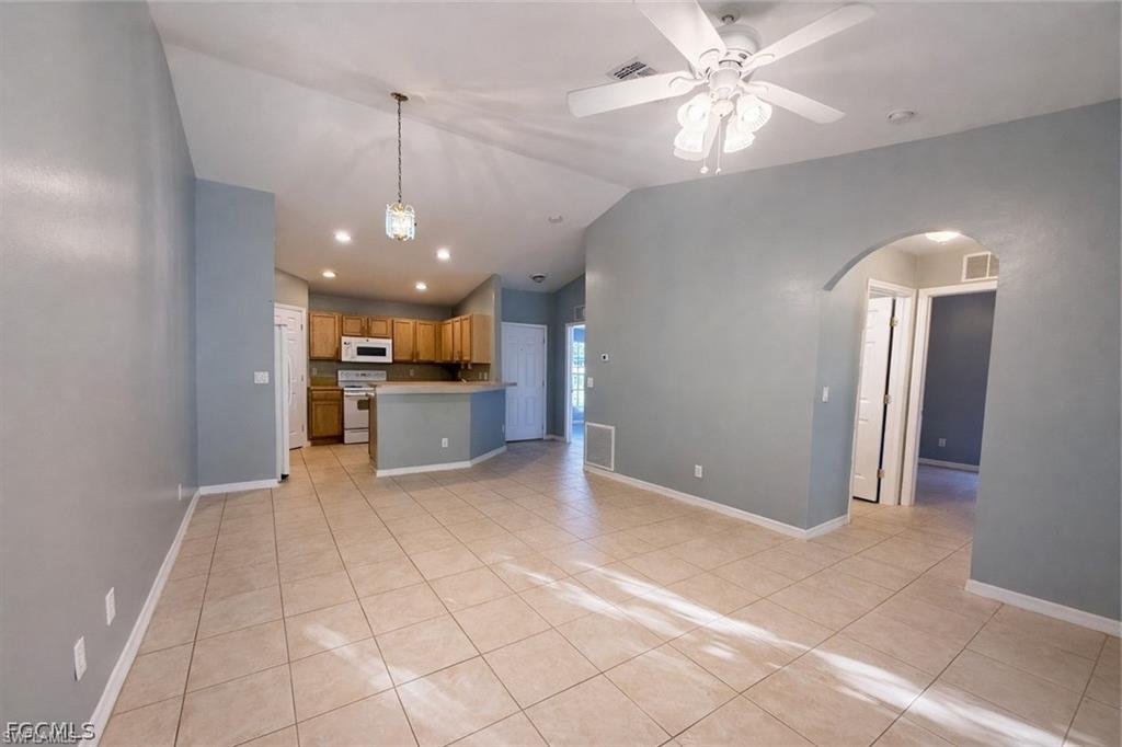Kitchen featuring lofted ceiling, ceiling fan, light tile patterned flooring, open floor plan, and hanging light fixtures