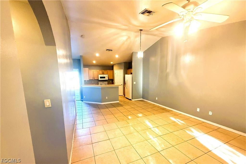 Unfurnished living room with vaulted ceiling, light tile patterned flooring, recessed lighting, ceiling fan, and arched walkways