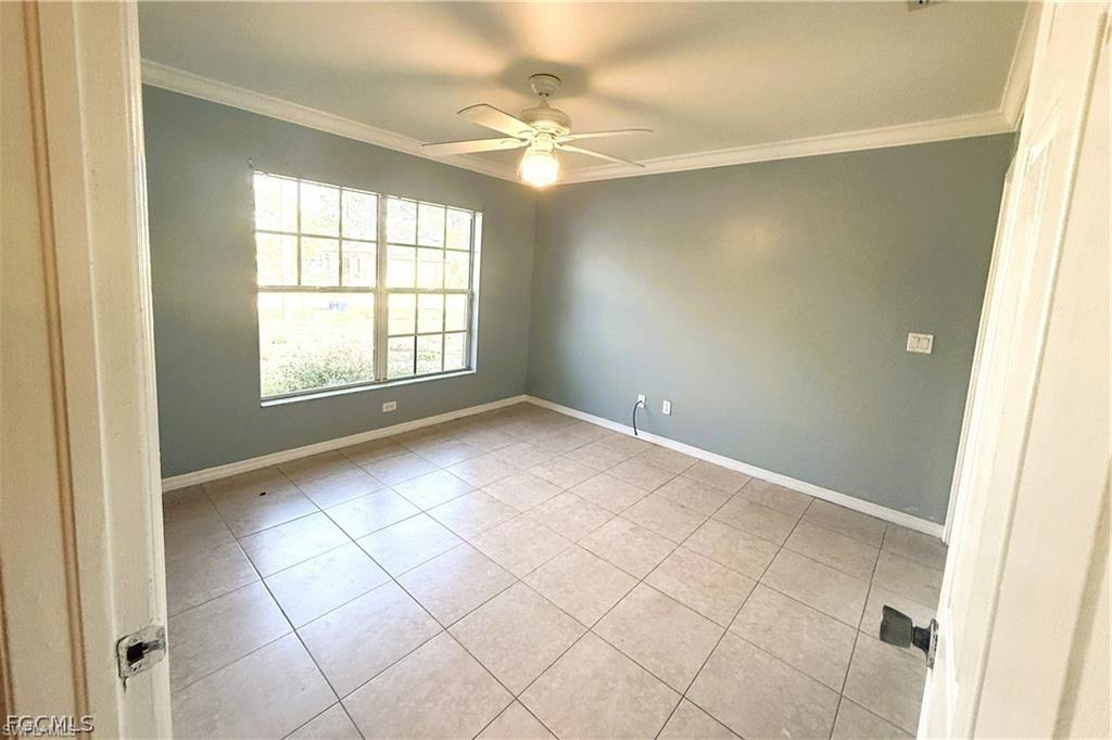 Unfurnished room with ornamental molding, a ceiling fan, and light tile patterned flooring