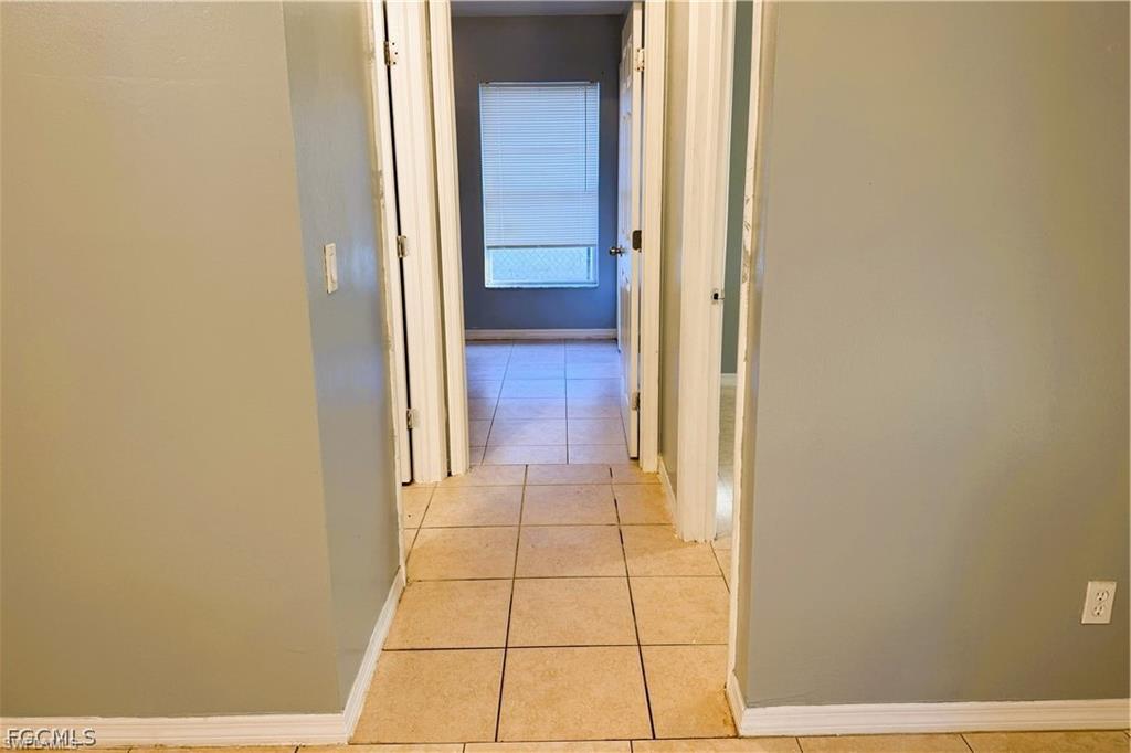 Hallway with baseboards and light tile patterned flooring