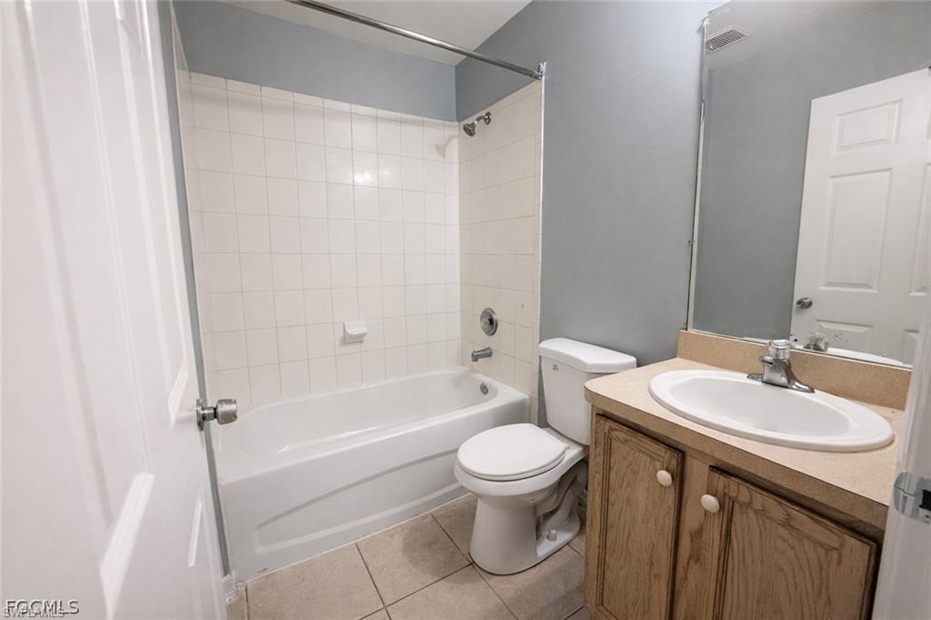 Bathroom with vanity, bathtub / shower combination, and light tile patterned floors