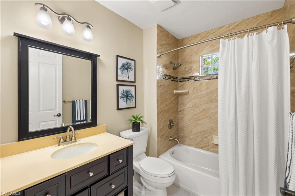 Full bathroom with toilet, shower / bathtub combination with curtain, and vanity