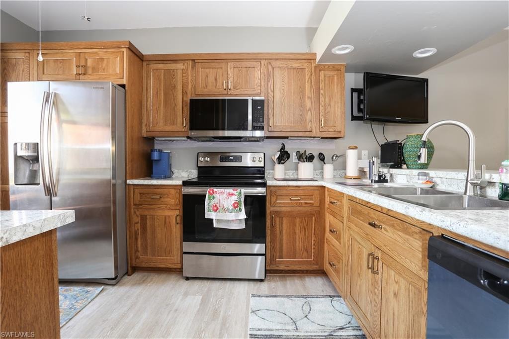Kitchen featuring stainless steel appliances, light countertops, light wood-style flooring, and wood finish cabinetry