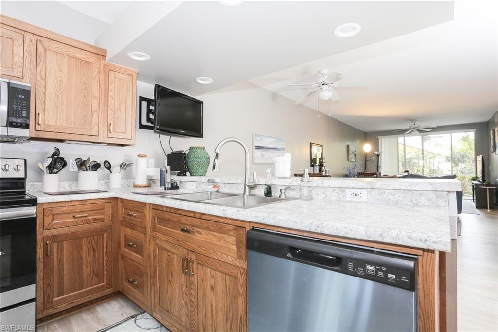 Kitchen with stainless steel appliances, light countertops, a peninsula, open floor plan, and a ceiling fan